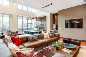 club room at crest at skyland town center apartments with large sofa and tv