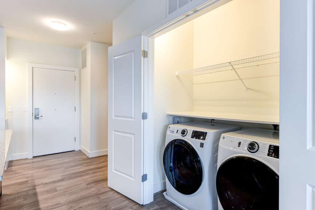 Two bedroom b laundry closet with side by side washer and dryer and folding table