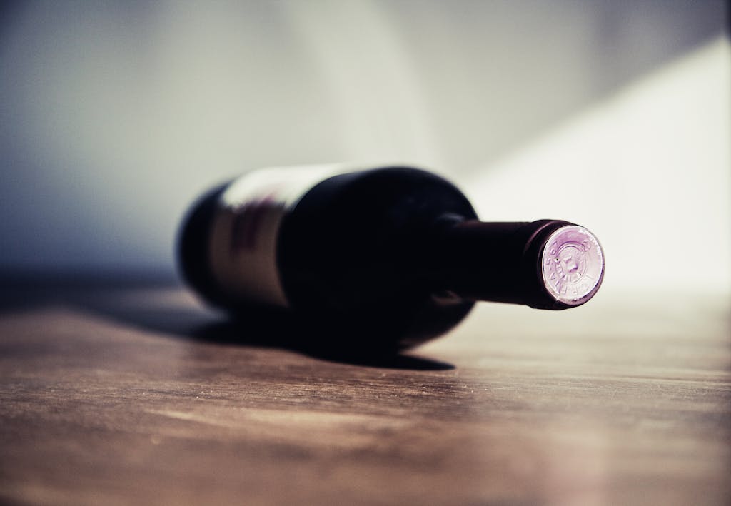 Close-up of a wine bottle on a wooden table, showcasing elegant shadows and soft lighting.