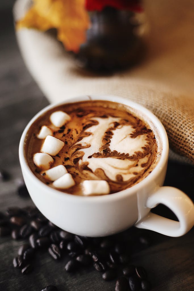 Delicious hot chocolate topped with marshmallows and latte art, perfect for cozy autumn days.